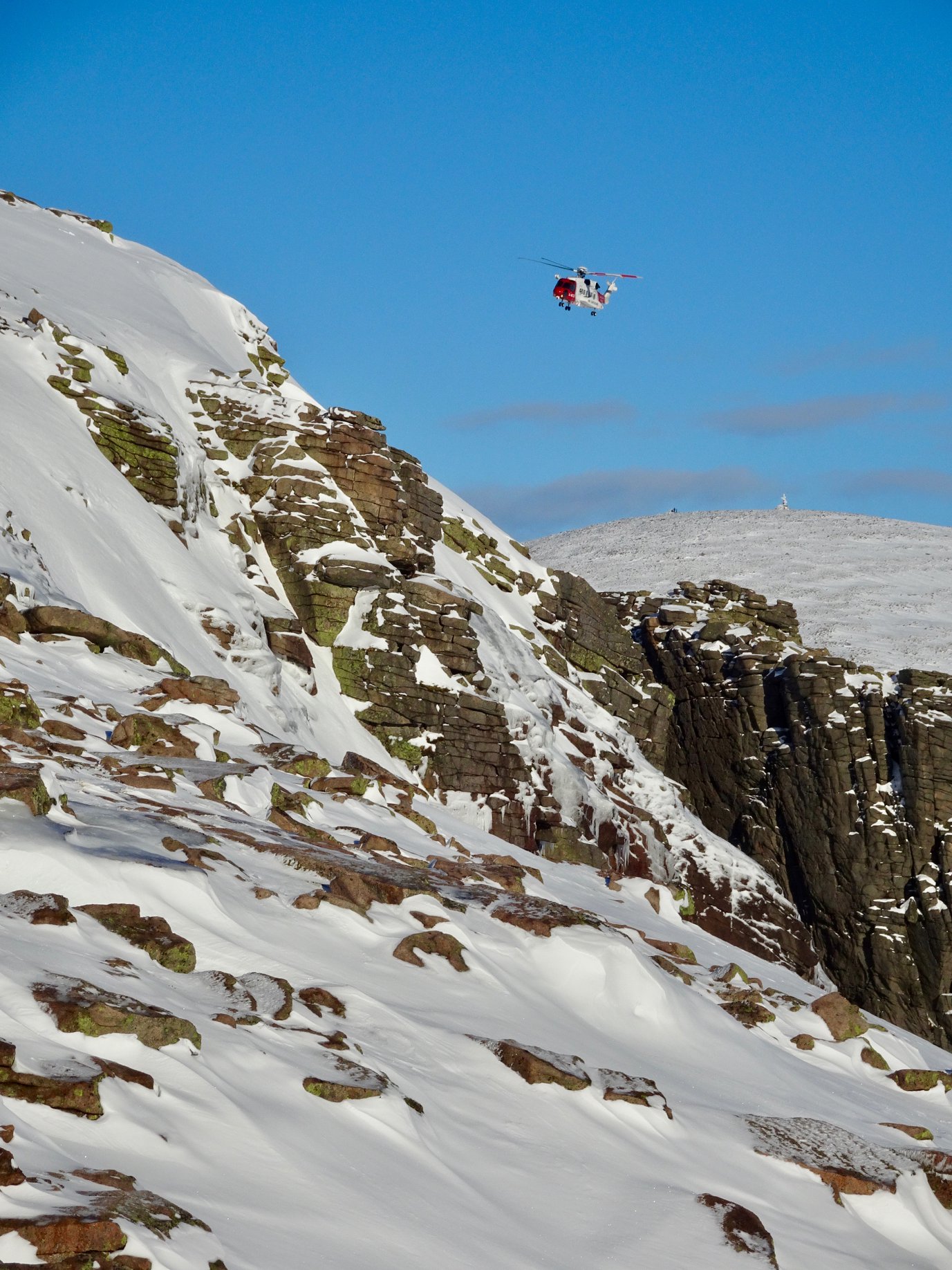 Cairngorm mountain rescue team winch someone to safety from a helicopter just about Loch Avon